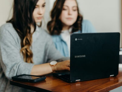 two woman using laptop