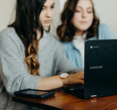 two woman using laptop
