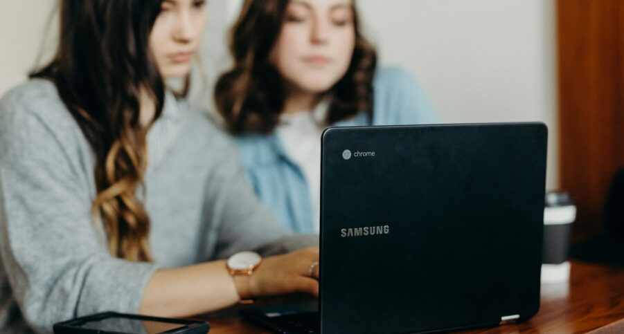 Two women sitting in front of a laptop looking at website design